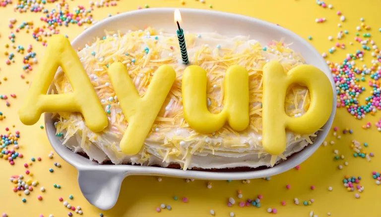 AI generated image of a birthday cake with one candle in the shape of the Ayup Creative logo